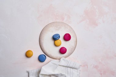 Dekoratif masa stili ve zemin üzerinde renkli badem kurabiyesi, el ve tabak stili, yukarıdan görünüm.