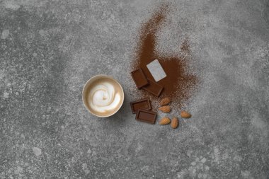 Seramik cam kahve stili, arka planda çikolata ve badem, gri dekoratif tasarım..