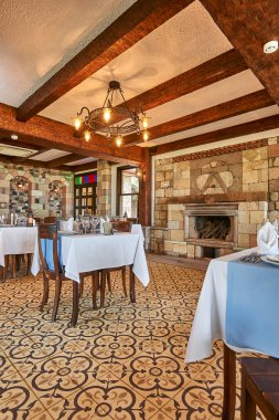 Taş ve ahşap konsept restoran, masa ve sandalye, bardaklar, dekoratif yemekler. Otel restoranı.