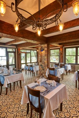 Taş ve ahşap konsept restoran, masa ve sandalye, bardaklar, dekoratif yemekler. Otel restoranı.