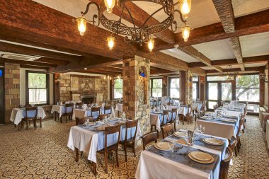 Taş ve ahşap konsept restoran, masa ve sandalye, bardaklar, dekoratif yemekler. Otel restoranı.