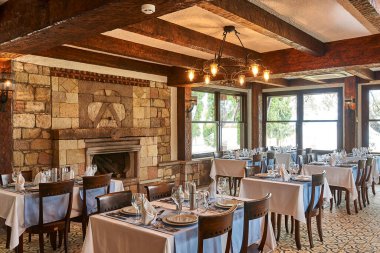 Taş ve ahşap konsept restoran, masa ve sandalye, bardaklar, dekoratif yemekler. Otel restoranı.