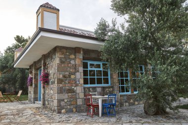 Taş ev, dekoratif pencere, bahçe, ahşap sandalye ve masa, zeytin ağacı, dışarıda..