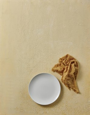 Beyaz boş tabak, dekoratif desenli peçete. Yukarı görünüm.