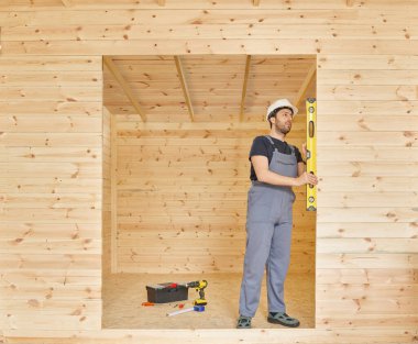 İnşaatçı, inşaatçı yeni ahşap ev yapar, küçük ev tarzı. Ruh seviyesi, vida, alet çantası ve dolu matkap. Ahşap sitili.