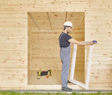 İnşaatçı, inşaatçı yeni ahşap ev yapar, küçük ev tarzı. Ruh seviyesi, vida, alet çantası ve dolu matkap. Ahşap sitili.