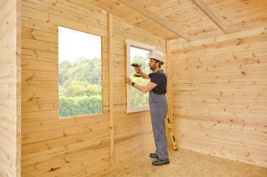 İnşaatçı, inşaatçı yeni ahşap ev yapar, küçük ev tarzı. Ruh seviyesi, vida, alet çantası ve dolu matkap. Ahşap sitili.