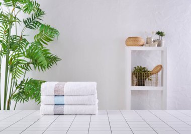 Arka arkaya beyaz ve gri havlular, banyo odası eşyalarıyla dolu vazo..