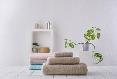 Kahverengi ve renkli havlu sıranın arkasında, beyaz duvar ve dolap arka plan duvarı, banyo nesnesi.