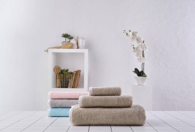 Kahverengi ve renkli havlu sıranın arkasında, beyaz duvar ve dolap arka plan duvarı, banyo nesnesi.