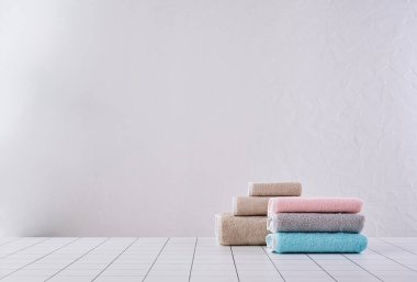 Kahverengi ve renkli havlu sıranın arkasında, beyaz duvar ve dolap arka plan duvarı, banyo nesnesi.