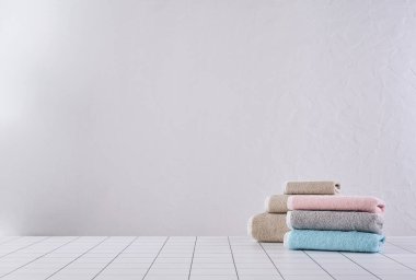 Kahverengi ve renkli havlu sıranın arkasında, beyaz duvar ve dolap arka plan duvarı, banyo nesnesi.