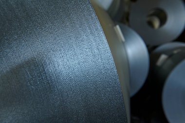 Galvanize çelik bobin detayı ve fabrika arka planı.