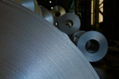 Galvanize çelik bobin detayı ve fabrika arka planı.