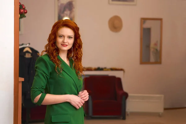a room providing a space out of which one or more other rooms or corridors lead.Young red haired smiling woman in a green in the lobby of the hotel restaurant.