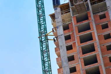 a large, tall machine used for moving heavy objects by suspending them from a projecting arm or beam. Construction high crane,building and blue cloud sky. 