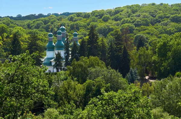 Christian monastery temple among densely growing trees on a warm sunny day
