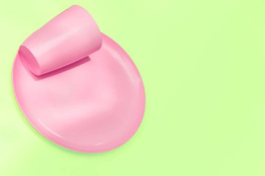 Kamp için pembe plastik bardak ve tabak, açık yeşil üzerine izole edilmiş.                               
