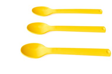 Sarı plastik yürüyüş kamp kaşıkları beyaz bir yüzey üzerinde                               