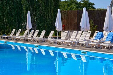 Tatil köyünde insanların yüzmesini bekleyen güneşli havuz.                               
