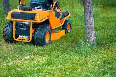 Profesyonel çimenleri mini traktör çim biçme makinesiyle biçiyor..