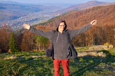 Neşeli turist bir dağın yamacında kollarını açmış duruyor.                               