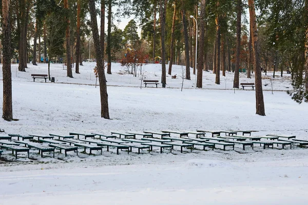 Benches for spectators at a summer concert venue cover with snow in winter park