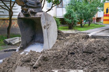  Kazı kovası toprağı kaldırıyor, yol onarımı için toprağı.                              