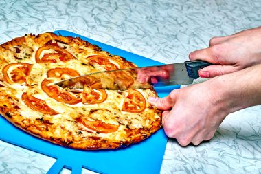 Yeni hazırlanmış pizzayı bıçakla kesiyorum. Fırında pizza yemeye hazırım.                               