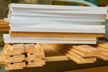 Bir depoda marangozların arasına dizilmiş kontrplak, tahta, kereste çarşafları.                               