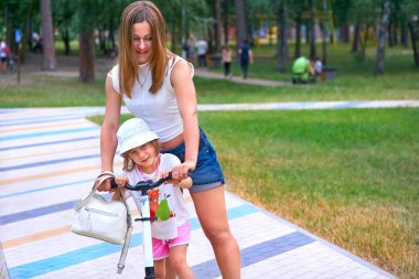 Genç, güzel bir kadın. Anne ve kızı. Bir yaz parkında motosikletle geziyorlar.