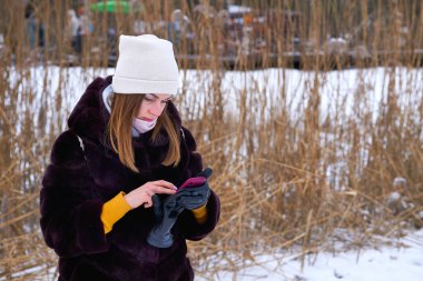 Genç, güzel bir kadın mesaj yazıyor, donmuş gölün yanında sohbet ediyor.