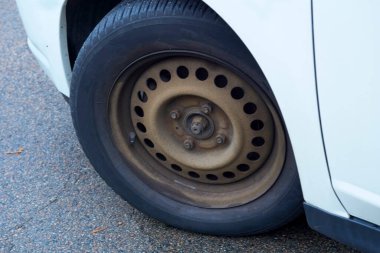 Paslı kenarlı kapağı olmayan bir arabanın ön tekerleği döndürülmüş. 