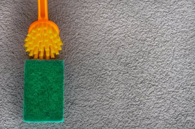 Gri alçılı yüzeyi temizlemek için turuncu fırça yeşil sünger