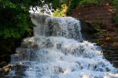 Ağaçlar ve yeşilliklerle kaplanmış kayalarda çağlayan şelale.