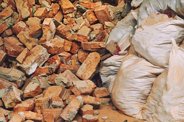 Kırık çöp torbaları. Bir yığın kırmızı tuğla parçası. Temizlik ve onarım