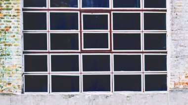 Eski tuğla duvarda beyaz çerçeveli siyah pencere