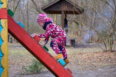 Oyun parkındaki merdivende oynayan sevimli bir çocuk.