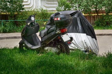 İki tekerlekli açık motorlu hafif bir araç. Sürücü kapalı bir motorun üzerinde oturuyor.