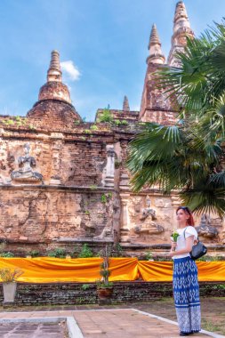 Geleneksel kostümlü genç Asyalı kadınlar Tayland 'da eski bir tapınağı ziyaret ediyorlar. Turist antik siteleri ziyaret ediyor.