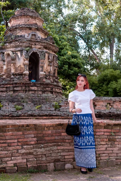 Geleneksel kostümlü genç Asyalı kadınlar Tayland 'da eski bir tapınağı ziyaret ediyorlar. Turist antik siteleri ziyaret ediyor.