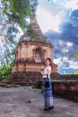 Geleneksel kostümlü genç Asyalı kadınlar Tayland 'da eski bir tapınağı ziyaret ediyorlar. Turist antik siteleri ziyaret ediyor.