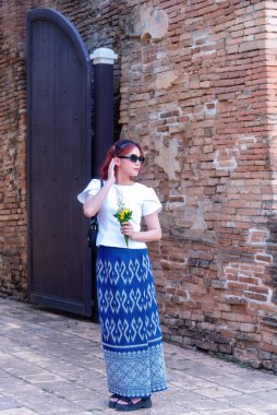 Geleneksel kostümlü genç Asyalı kadınlar Tayland 'da eski bir tapınağı ziyaret ediyorlar. Turist antik siteleri ziyaret ediyor.