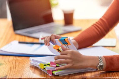 İş kadını elleri, işyerindeki tahta masalardaki kağıt yığınlarında arama yapmak için çalışıyor. İş Konsepti.