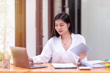 Ofiste dizüstü bilgisayarın önünde çalışan Asyalı bir iş kadını. Asya iş gündelik konsepti.