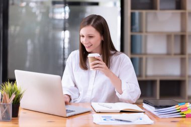 Ofiste dizüstü bilgisayarın önünde çalışan bir iş kadını. Ticaretin gelişigüzel ve başarılı kavramı