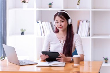 Asyalı kadınlar kulaklık takarlar müzik dinlerler gevşeyip dijital tablet kullanırlar. İnternetten öğrenen güzel bir kadın. Kulaklık takar ve çalışır..