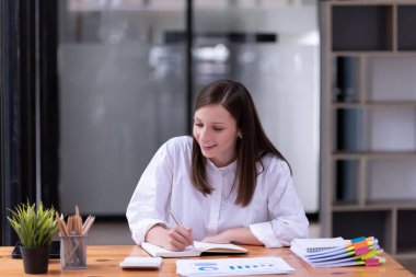 Ofisteki bir masada evraklar ve belgelerle çalışan genç bir iş kadını. Ticaretin gelişigüzel ve başarılı kavramı