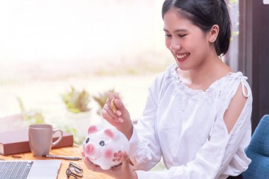 Eldeki madeni paralar domuz kumbaralarına bırakılıyor. Tahta bir masanın üstüne yığılmış nakit para, tasarruf konsepti..