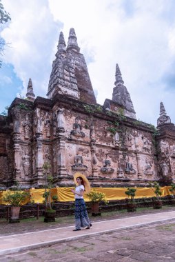 Geleneksel kostümlü genç Asyalı kadınlar Tayland 'da eski bir tapınağı ziyaret ediyorlar. Turist antik siteleri ziyaret ediyor.